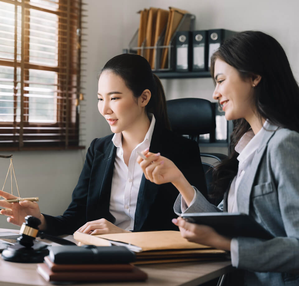 Aposentado sentado em frente a um advogado, ambos observando documentos de benefício previdenciário.